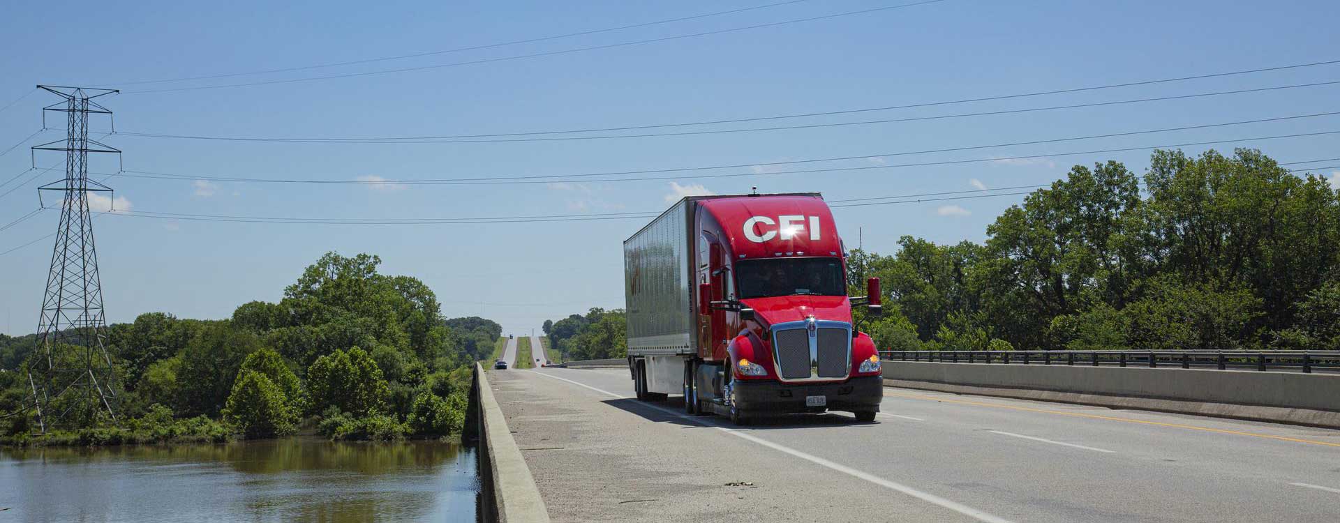 Red CFI tractor trailer driving over bridge